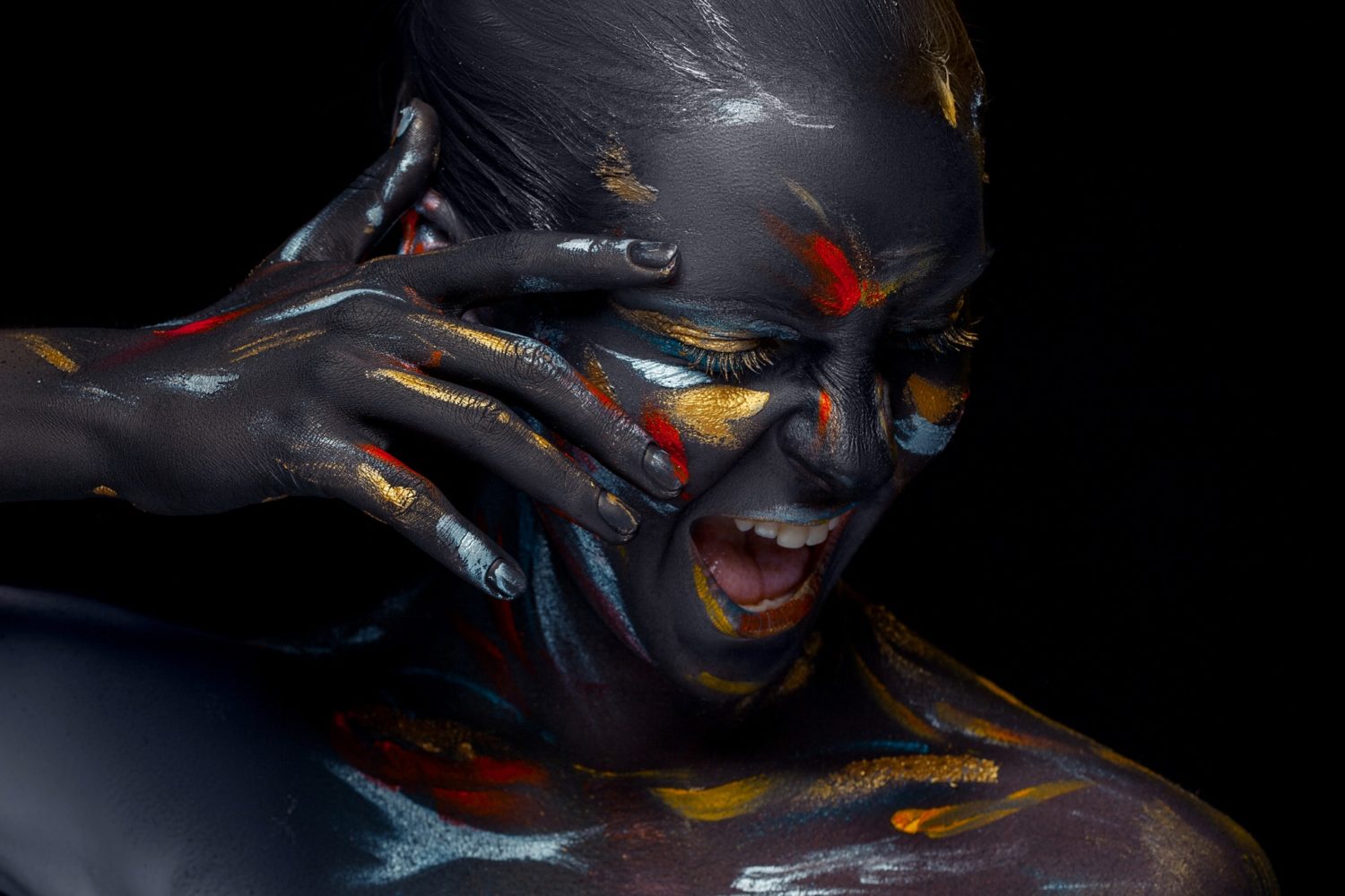 Portrait of a young woman who is posing covered with black paint